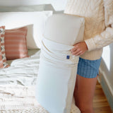Person holding a large white Stitchco pillow in a bedroom setting